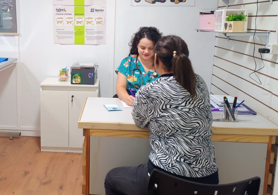 A veterinária Gabriela Lucena atendendo uma tutora na mesa do consultório
